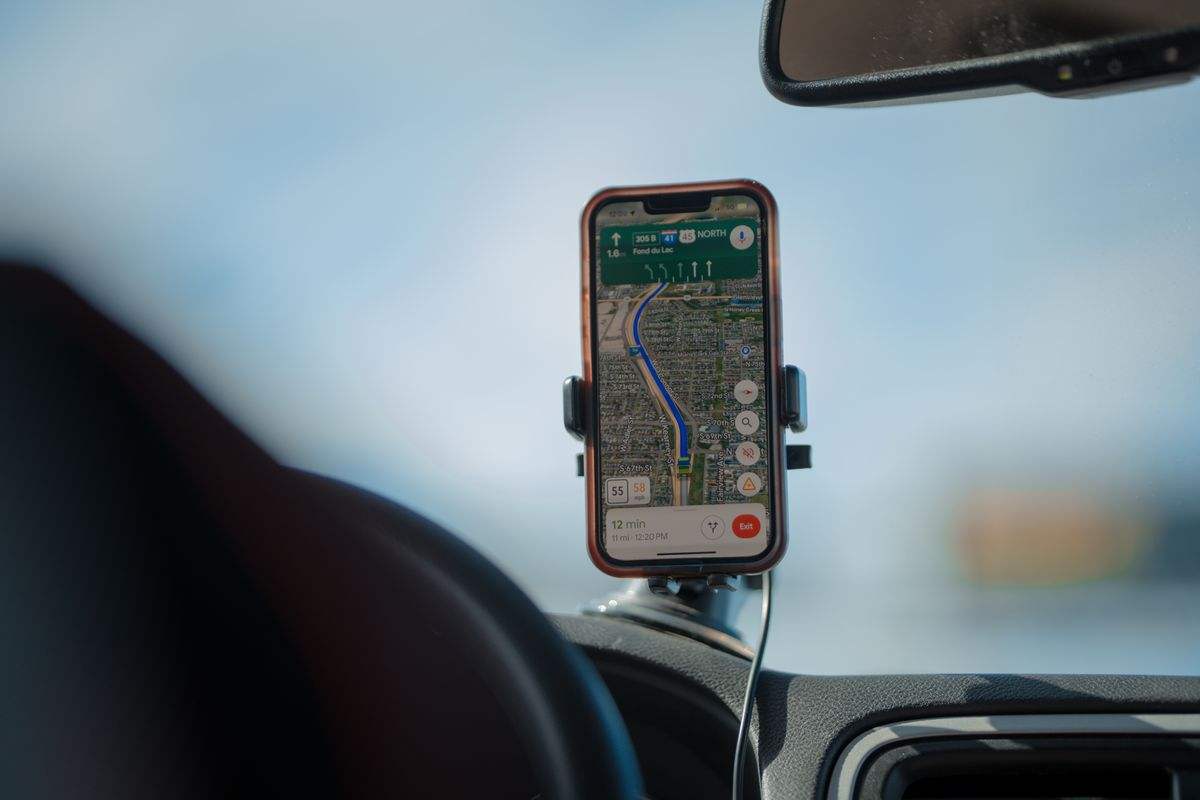Telefon v držáku v autě se zapnutou navigací