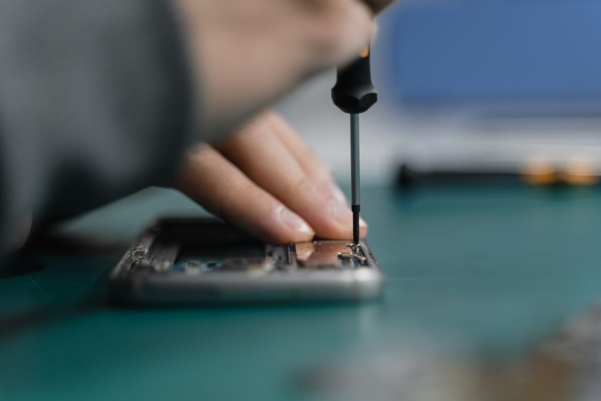 Servisní technik opravuje iPhone šroubovákem