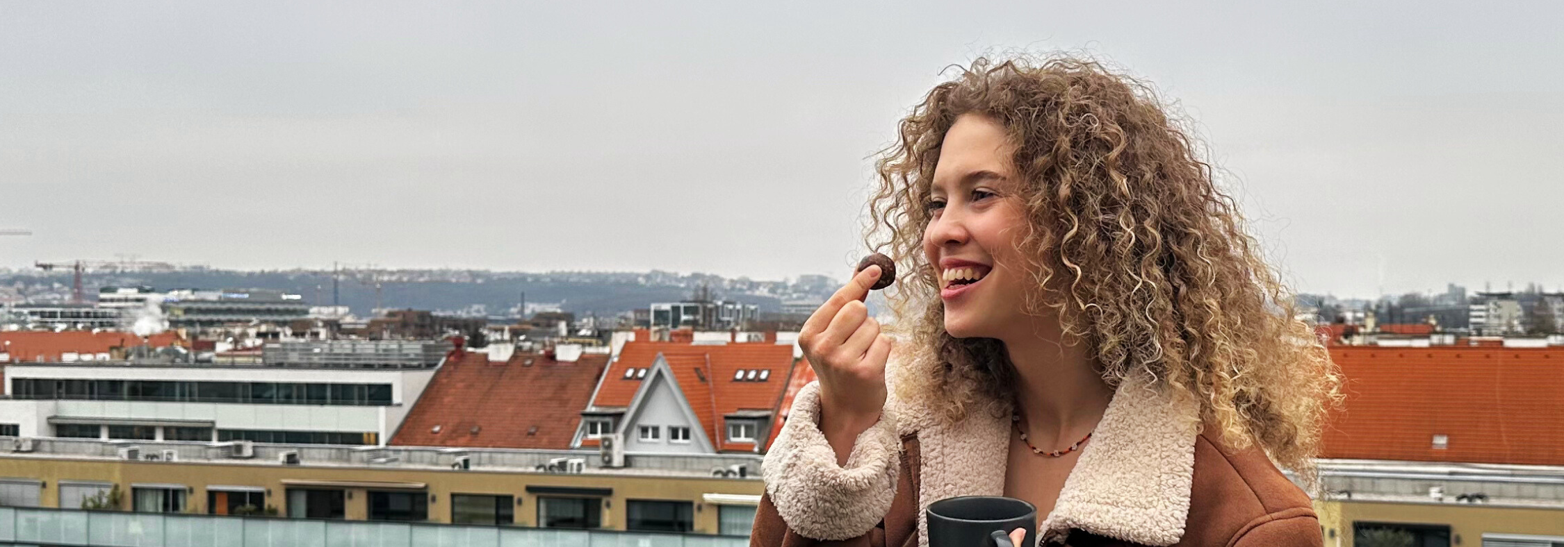 Žena stojící v přírodě se s úsměvem zakusuje do Energy Balls