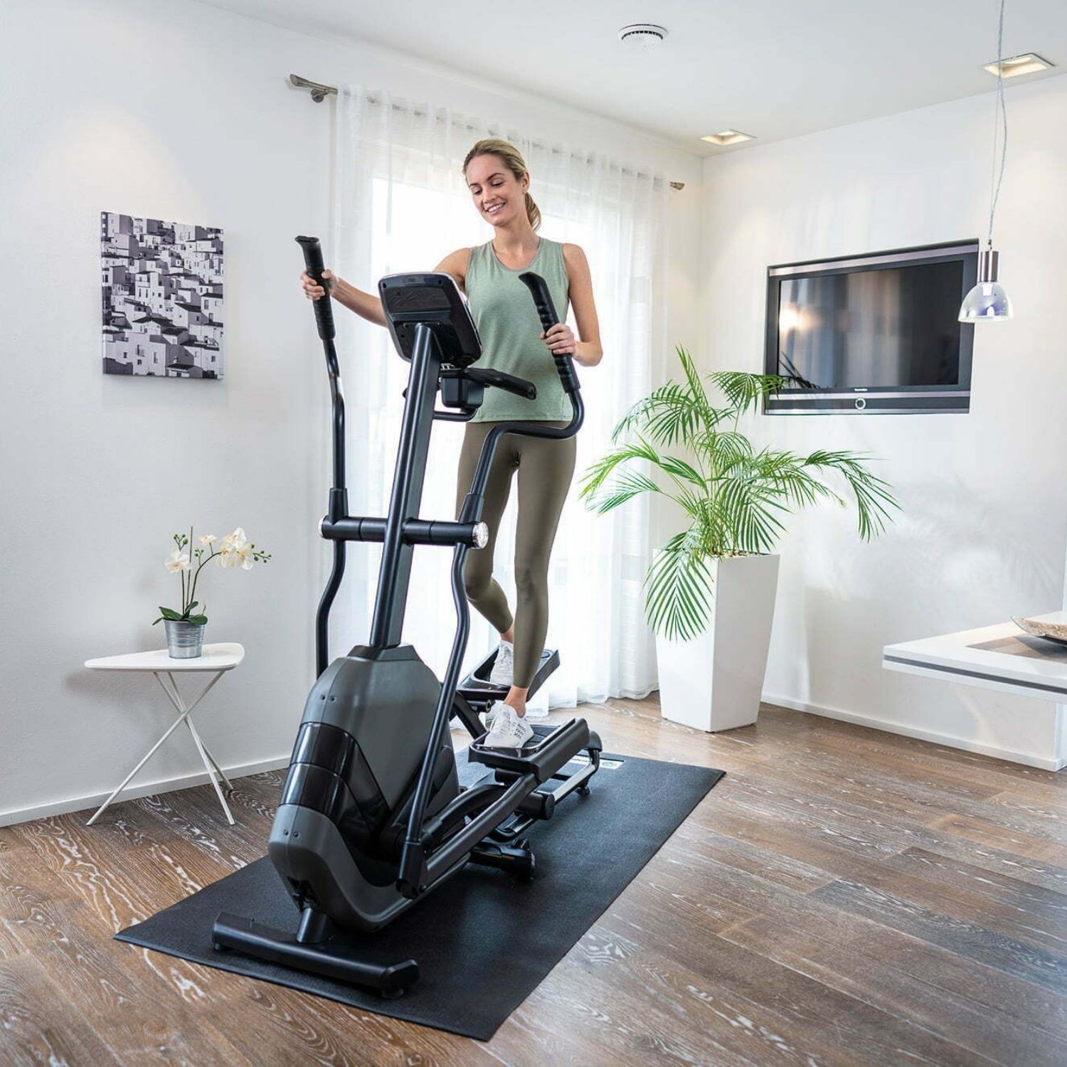 Žena cvičí na kompaktním eliptikalu Andes 7.1 v běžném bytě