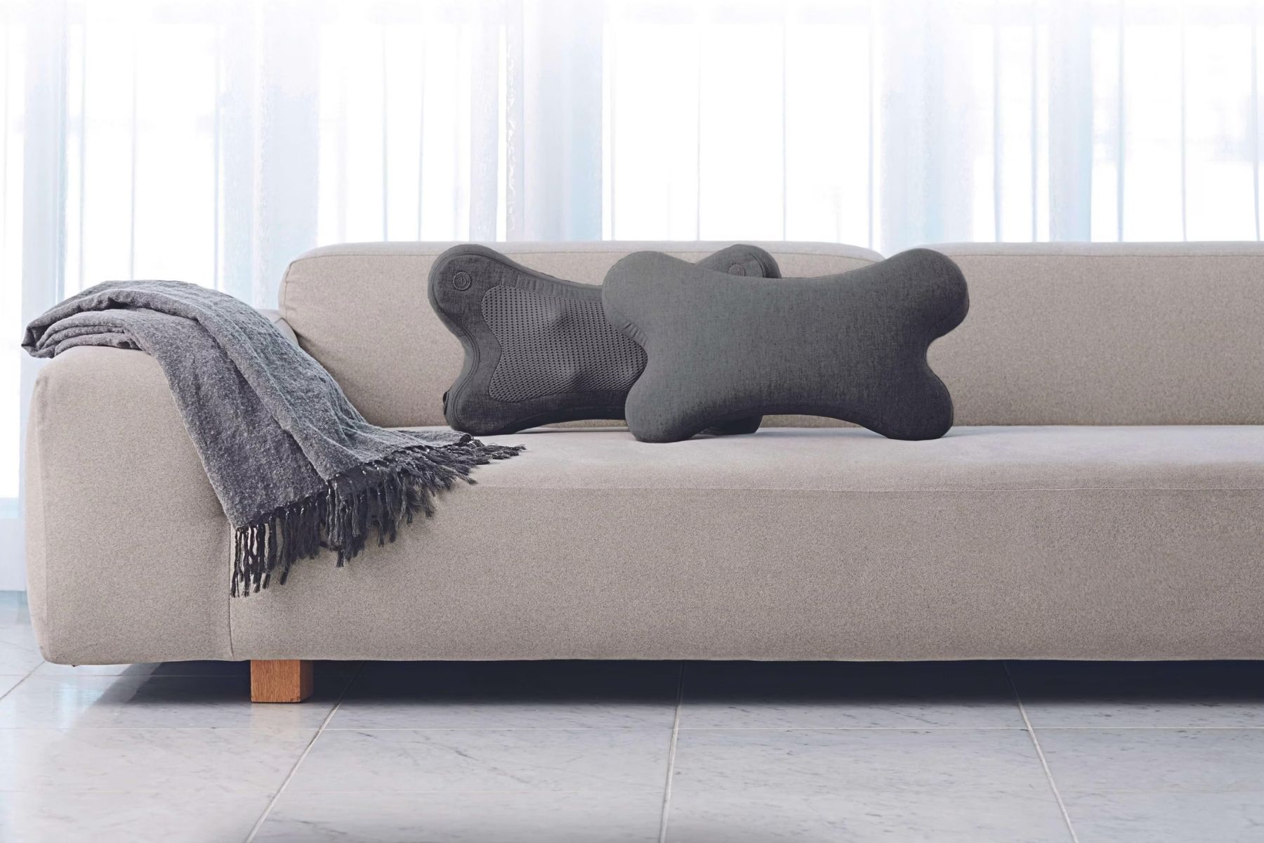 Dva bezdrátové masážní polštáře Synca iPuffy v elegantním minimalistickém designu na pohovce