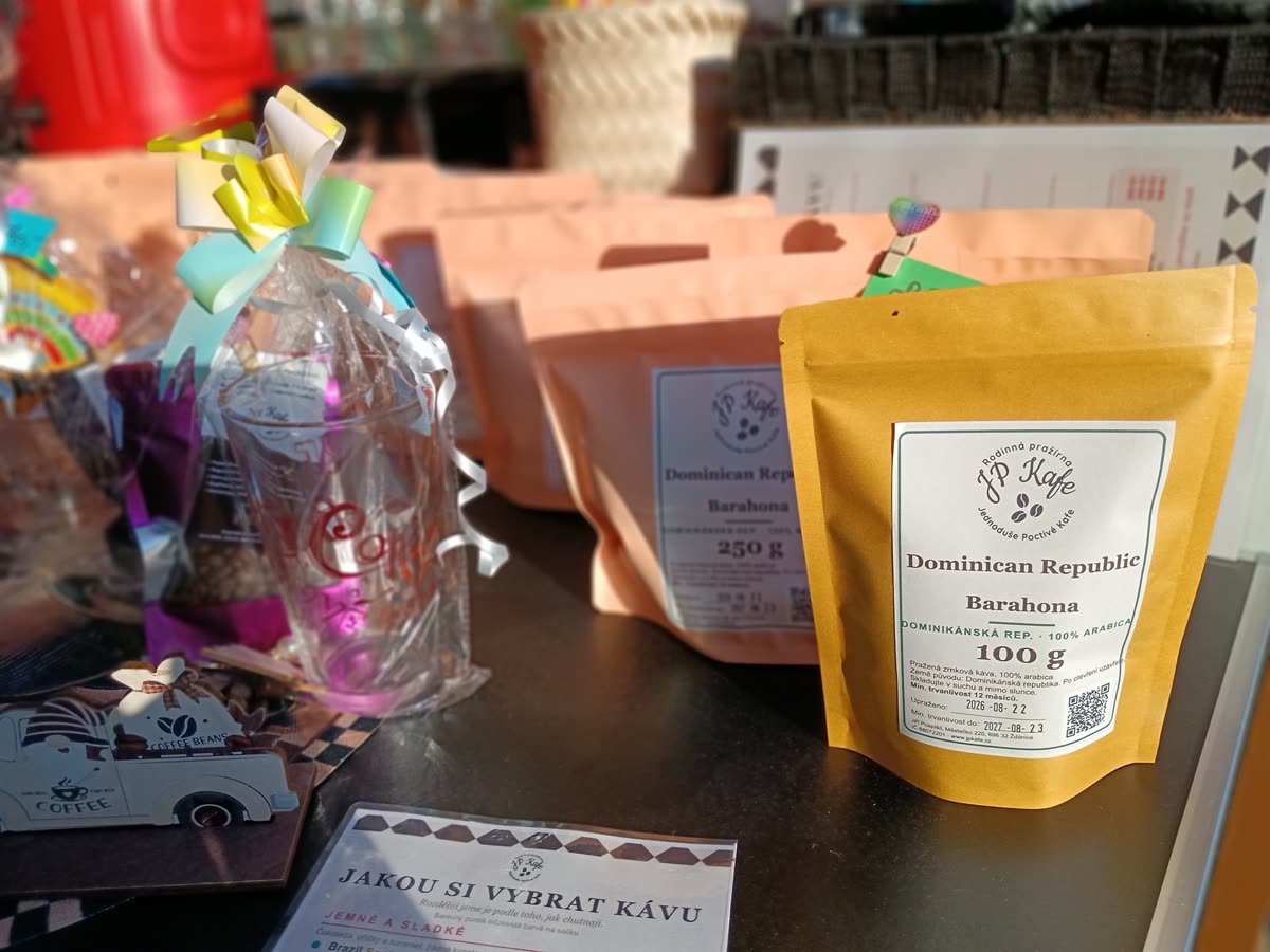 Sáčky s praženou kávou JP Kafe s etiketami, vedle nich leták Jakou si vybrat kávu