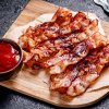 2052 3 pieces of fried bacon on a wooden cutting board 2024 09 22 17 41 43 utc