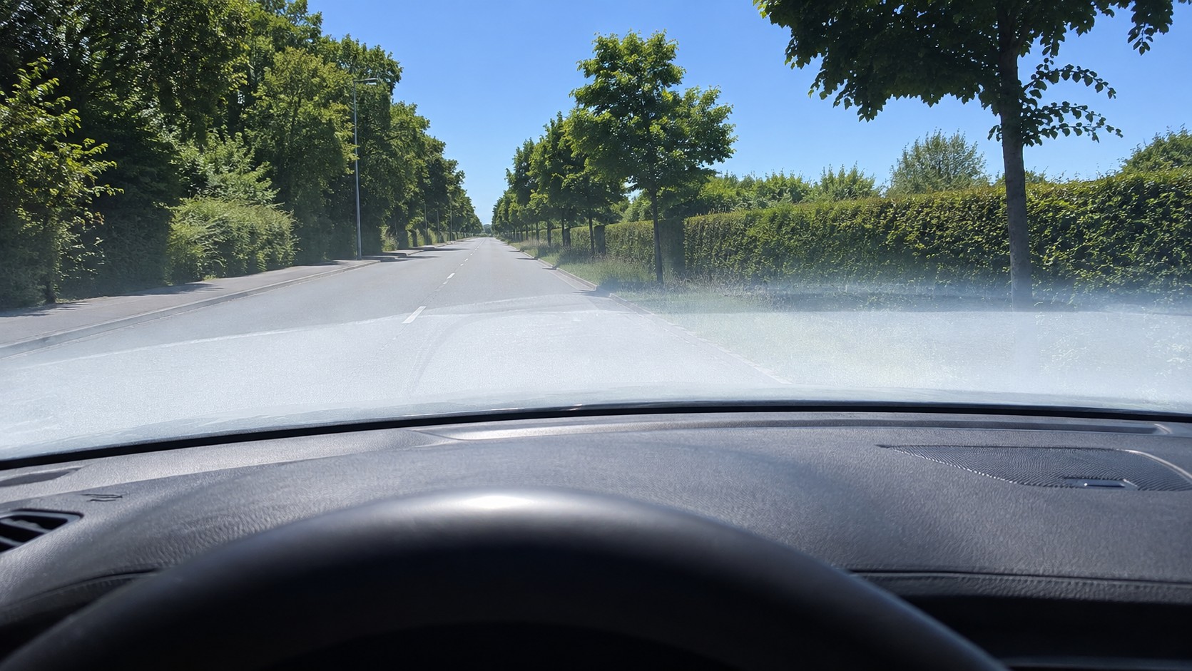 Lesklá palubná doska, ktorá sa odráža v čelnom skle auta.