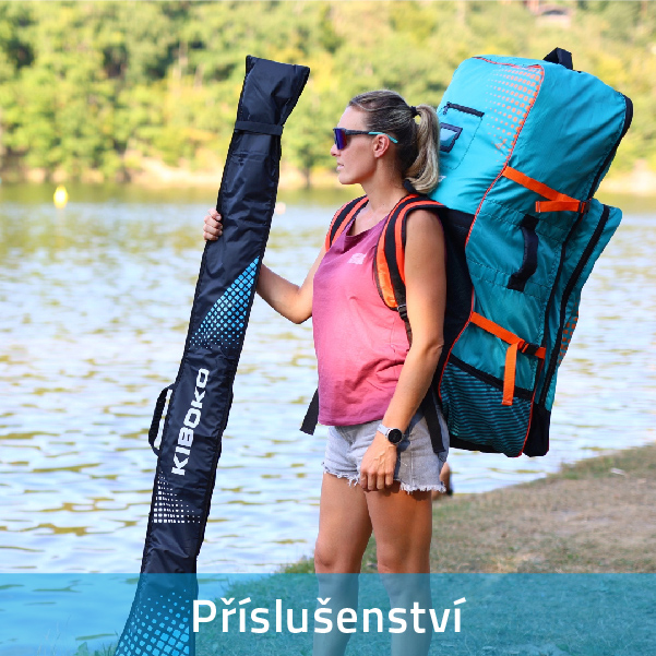 Sportovkyně stojící u vody s velkým batohem na paddleboard na zádech a držící pádlo v obalu