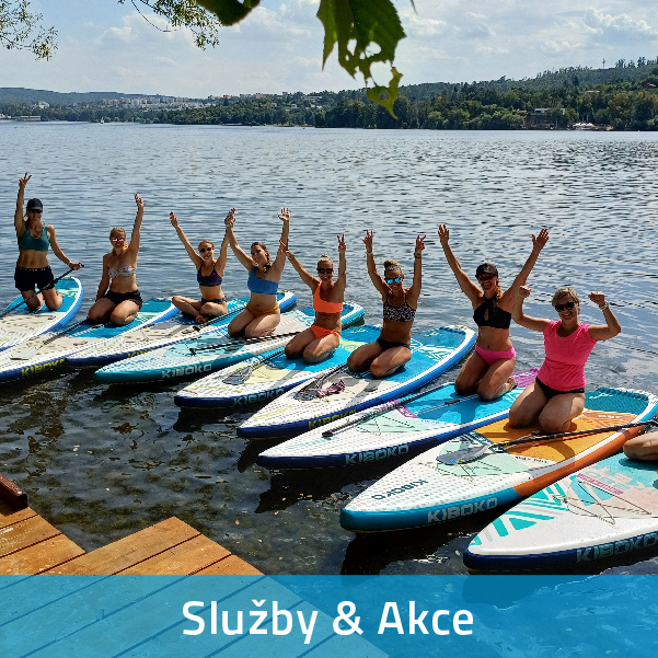 Početná skupinka lidí klečících a mávajících na paddleboardech a užívající si letní pohodu na vodě