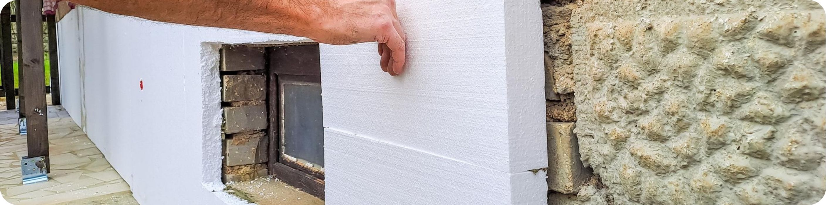 Muž pripevňuje tepelnú izoláciu na fasádu domu
