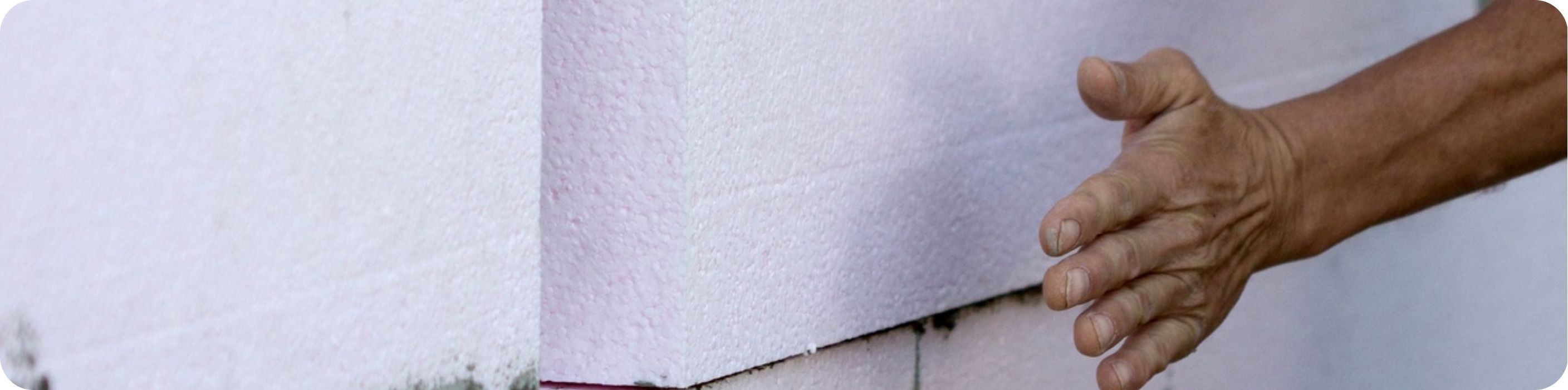 Muž pripevňuje tepelnú izoláciu na fasádu domu