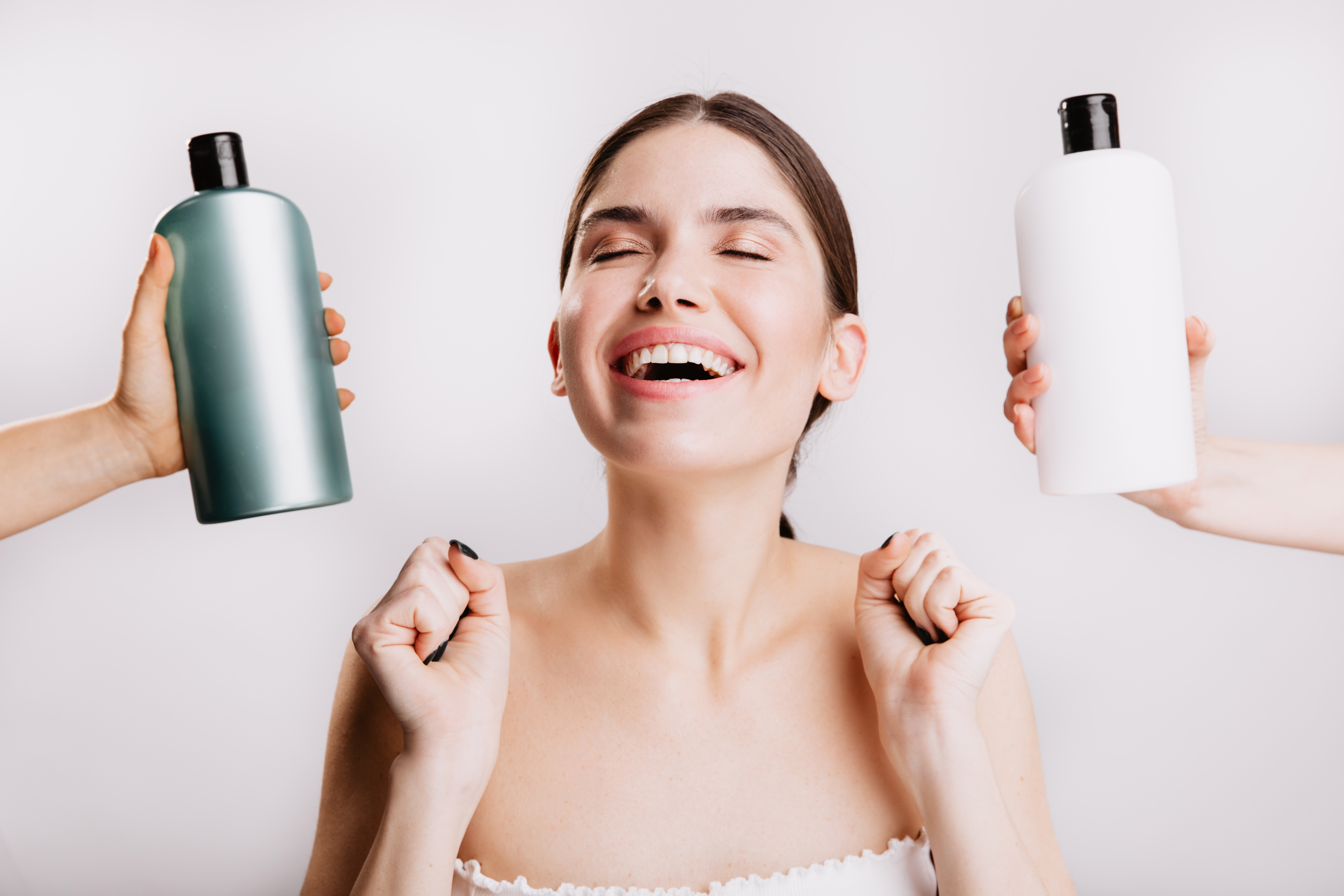 dark-haired-lady-happily-smiles-posing-isolated-wall-with-bottles-shampoos