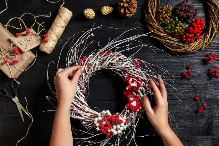 christmas-background-top-view-female-hands-make-christmas-wreath-packed-gifts-scrolls-spruce-branches-tools-wooden-table-workplace-preparing-handmade-decorations