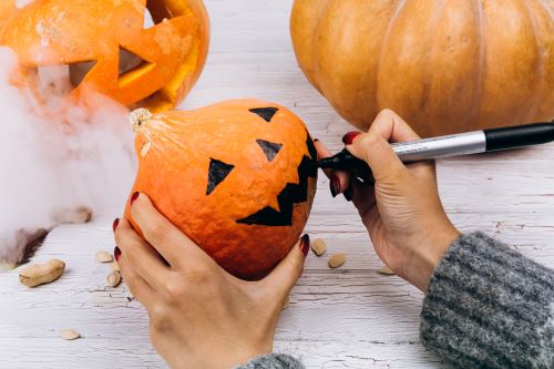 woman-paints-face-little-orange-pumpkin-halloween