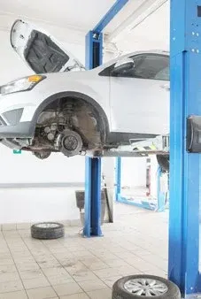 Automobil na zvedáku v autoservisu, kde se pneumatické nářadí pohání stlačeným vzduchem