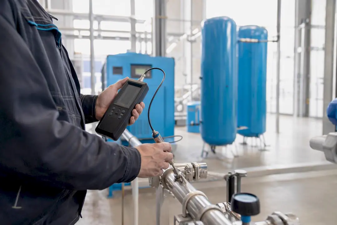 Technik nastavuje měřicí přístroj v komoře kompresoru
