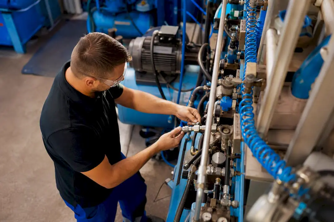 Technik kontroluje průmyslový systém stlačeného vzduchu
