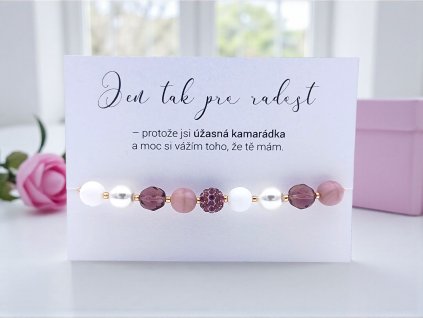 Náramek z bílých a fialových skleněných korálků s třpytivým středem, doplněný kartičkou „jen tak pro radost – protože jsi úžasná kamarádka“.