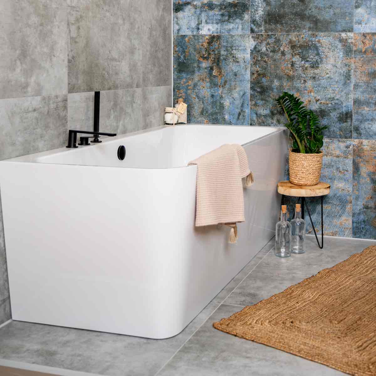 Moderní koupelna s designovými modrými obklady, volně stojící vanou, tmavými skříňkami a podsvíceným zrcadlem