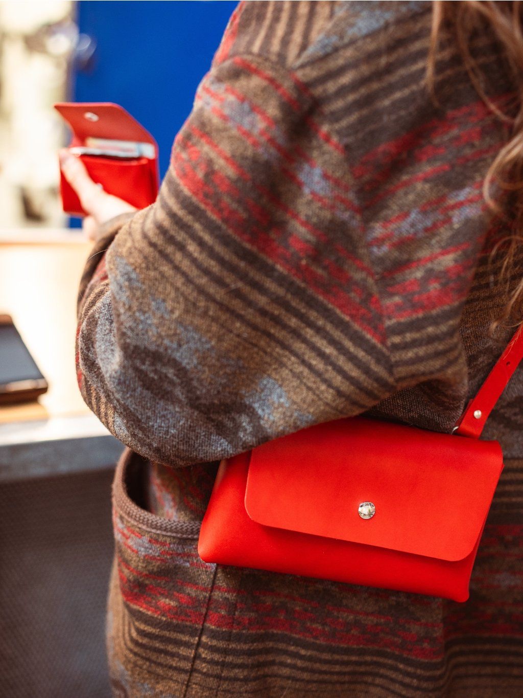 Reálná fotka: žena ve vlněném kardiganu s červenou Bellou crossbody v interiéru