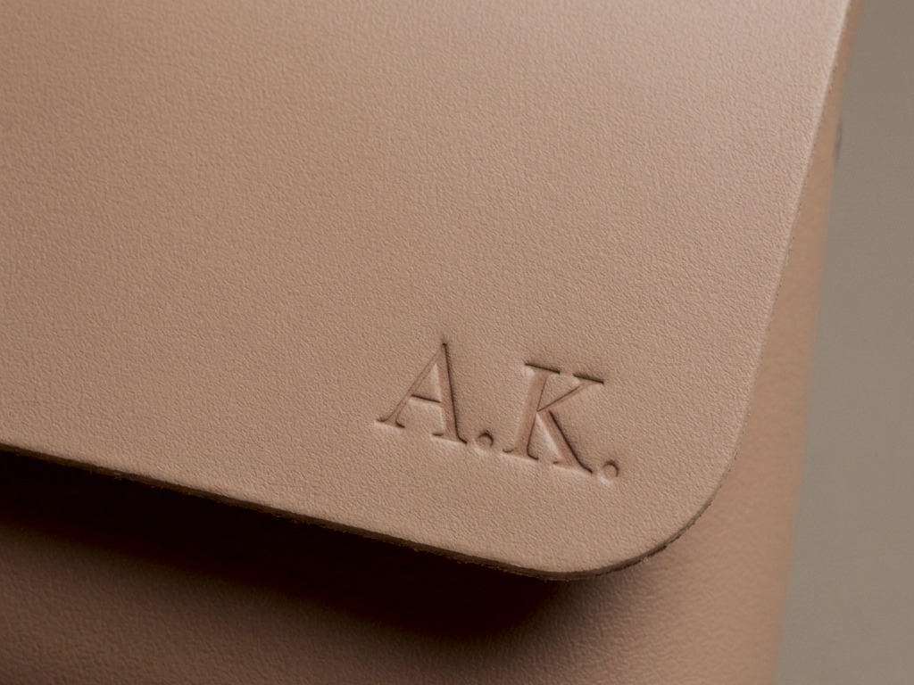Detail ražby iniciál A. K. v pravém dolním rohu klopy kabelky Bella taupe