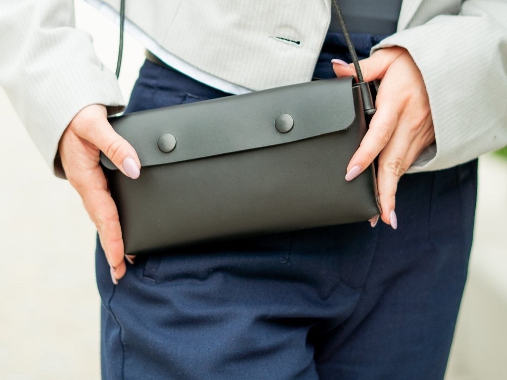Žena nosí koženou kabelku Laura v černé crossbody na dlouhém černém popruhu