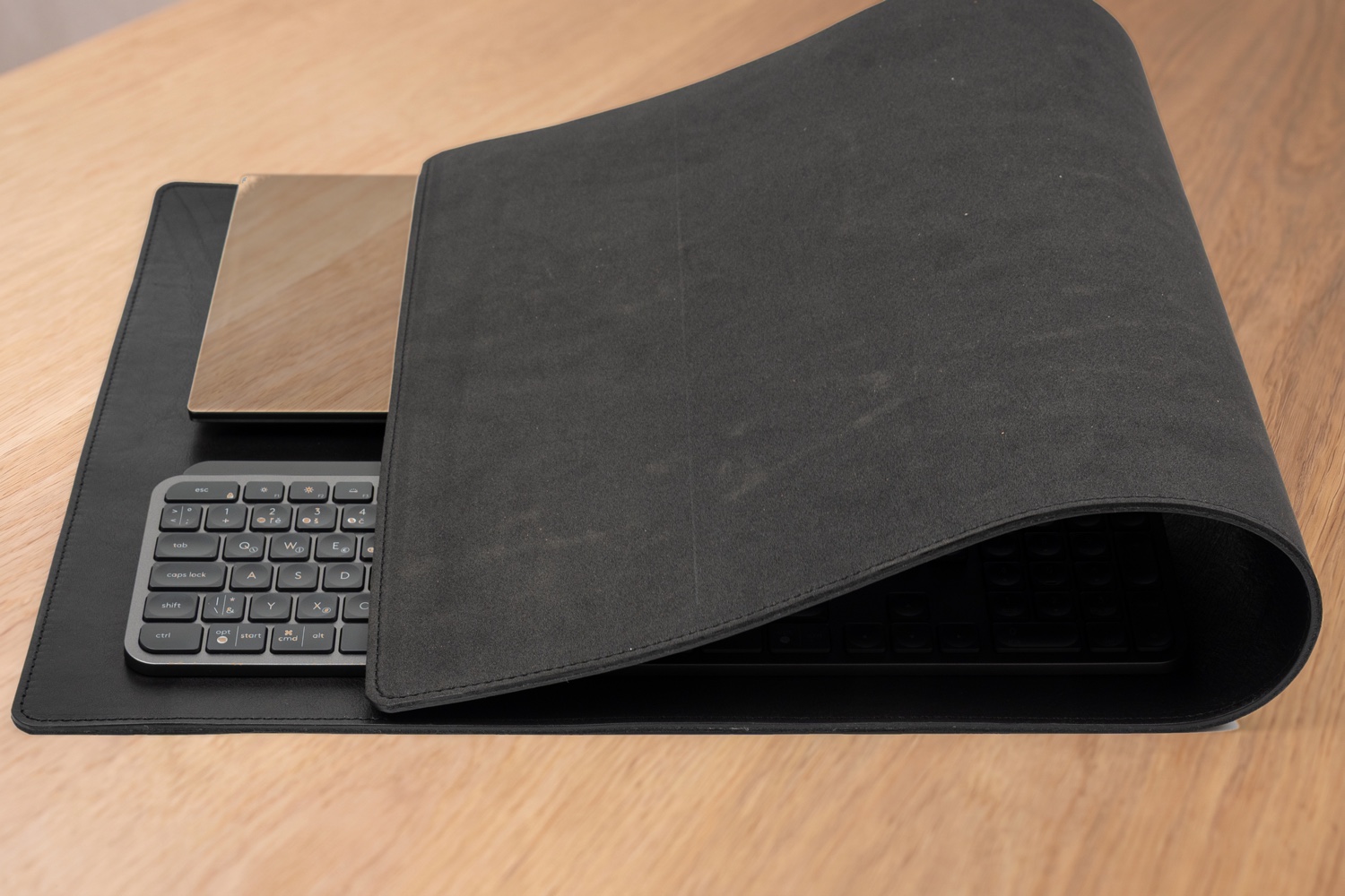 Přehnutá podložka Maxi ukazuje šedou protiskluzovou pěnovou spodní vrstvu, pod ní notebook a klávesnice