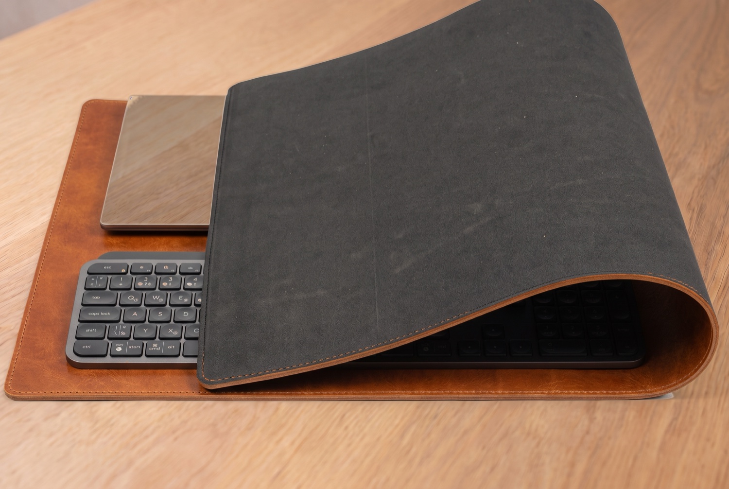 Přehnutá podložka Maxi ukazuje šedou protiskluzovou pěnovou spodní vrstvu, pod ní notebook a klávesnice