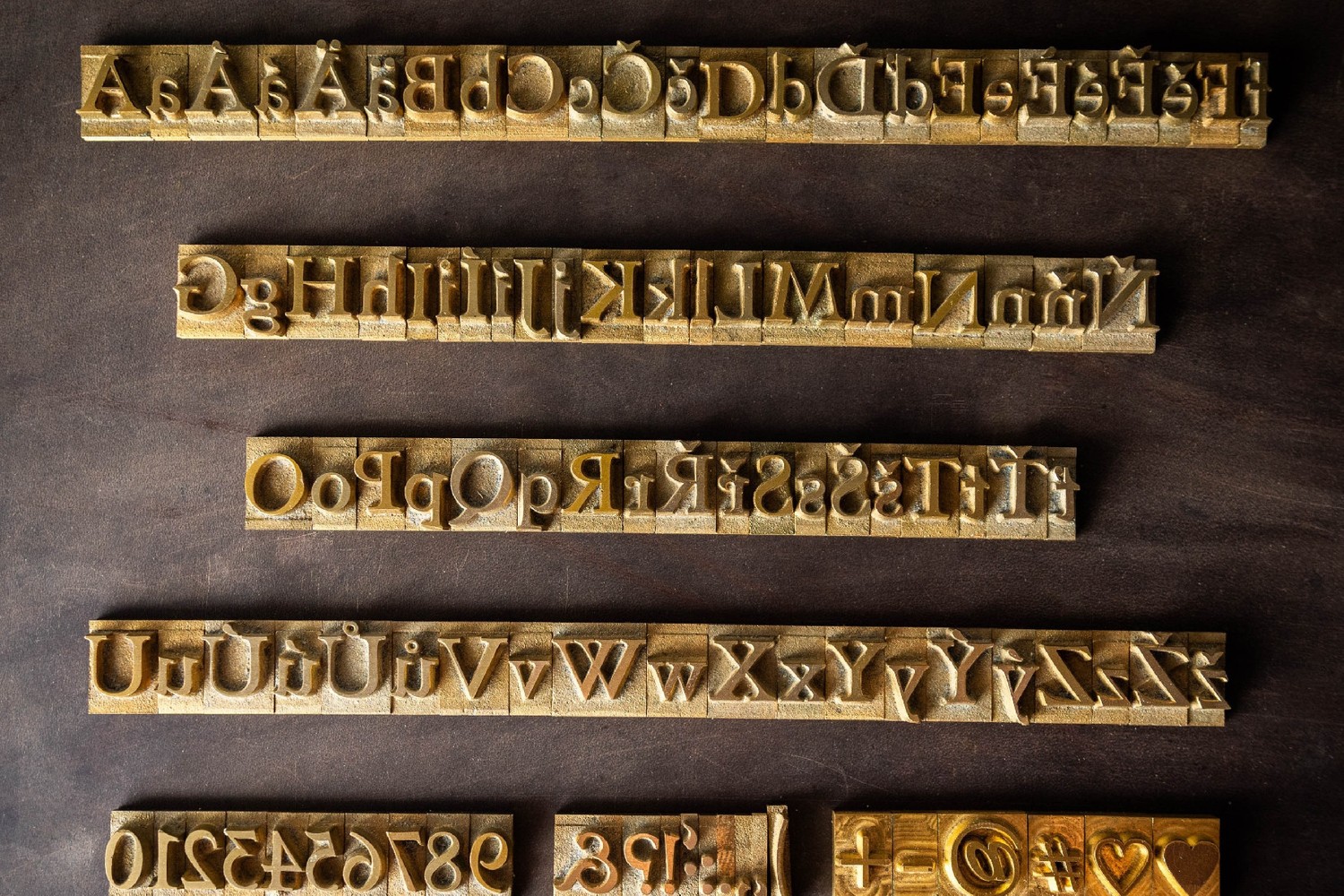 Mosazná razidla velké abecedy, kterými Kožedělník razí monogram do podložky Mickey