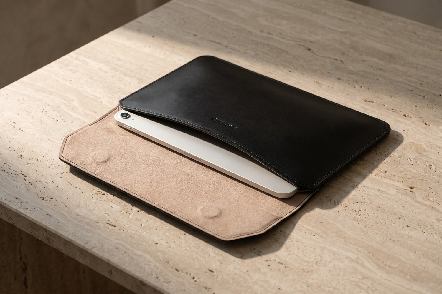Otevřené černé pouzdro na travertinovém stole, uvnitř béžové italské mikrovlákno a zasunutý tablet 11″