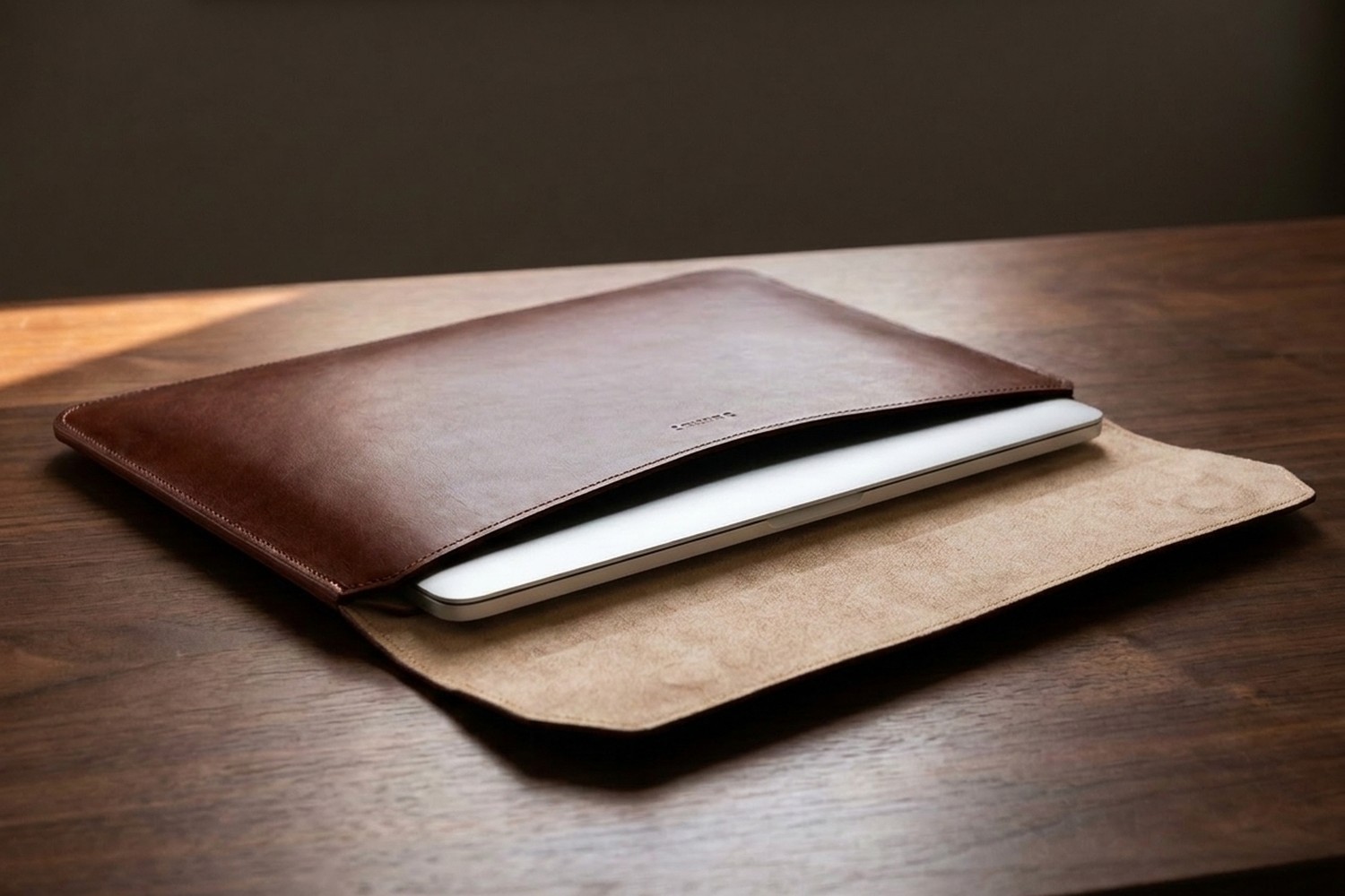 Otevřené hnědé pouzdro na ořechovém stole, uvnitř béžové italské mikrovlákno a zasunutý notebook 15″