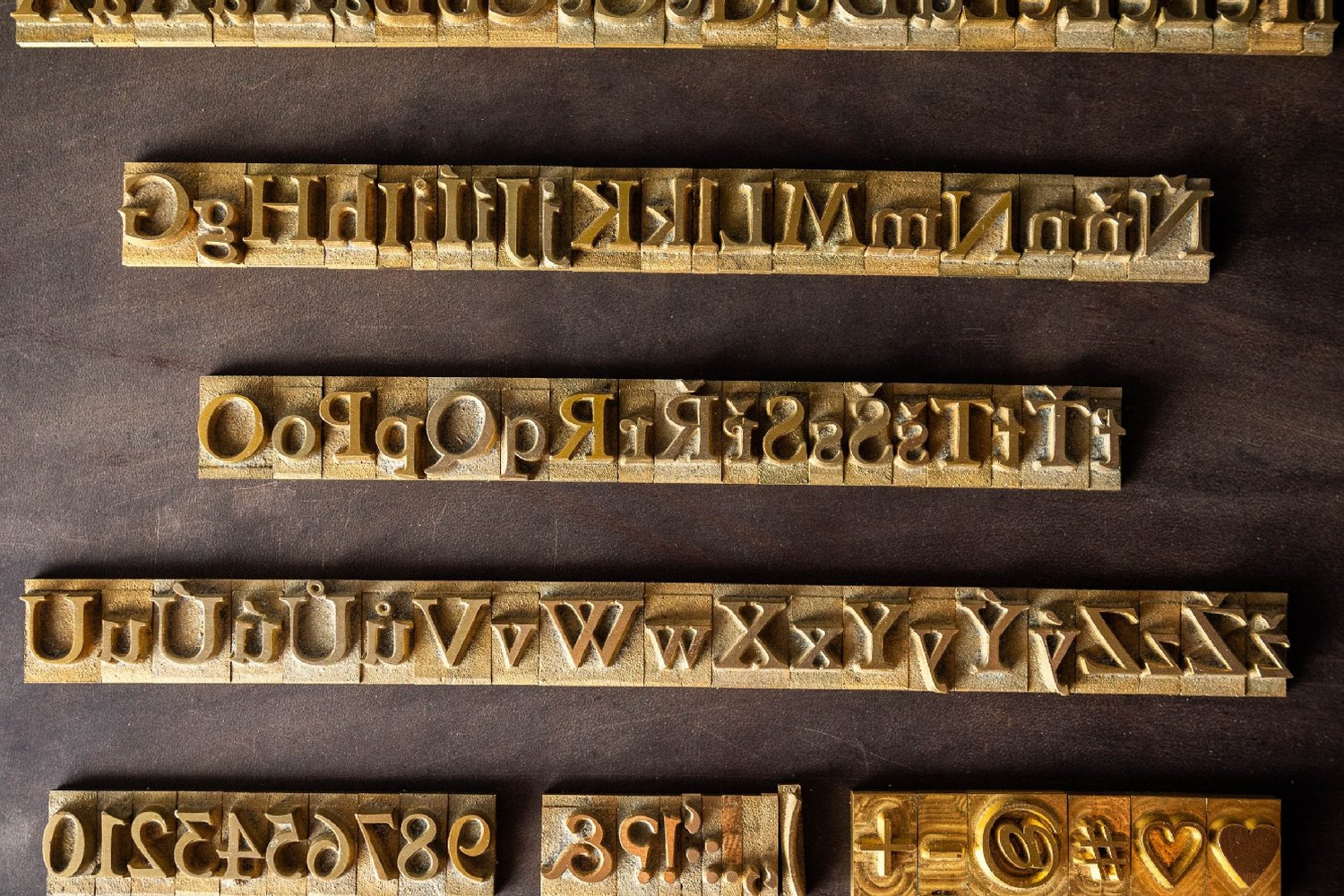Mosazná razidla velké abecedy, kterými Kožedělník razí monogram do klíčenky