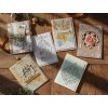 Realistic photo of five handmade Christmas cards arranged on a wooden table. Each card is created with a different technique – some made in scrapbook style with layered paper, ribbons, and small ornaments, others (3)