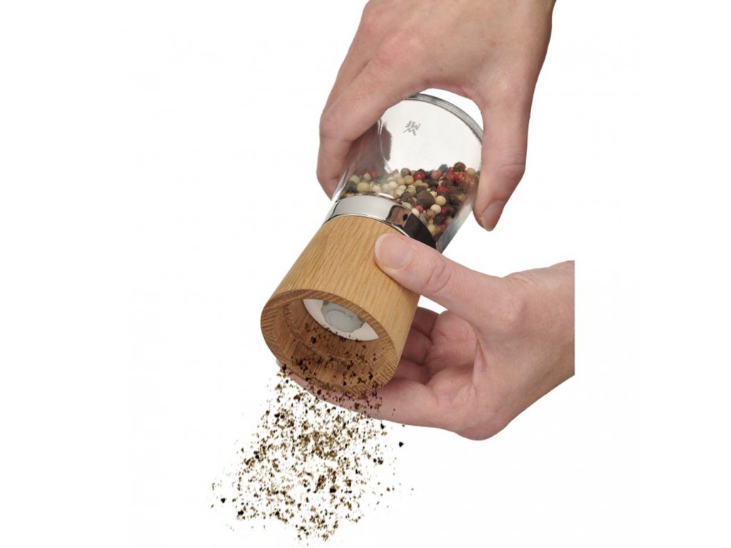 On a gray wooden surface lie spices, hand-made wooden pepper mill