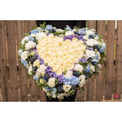 White and purple funeral heart arrangement with roses and delphiniums