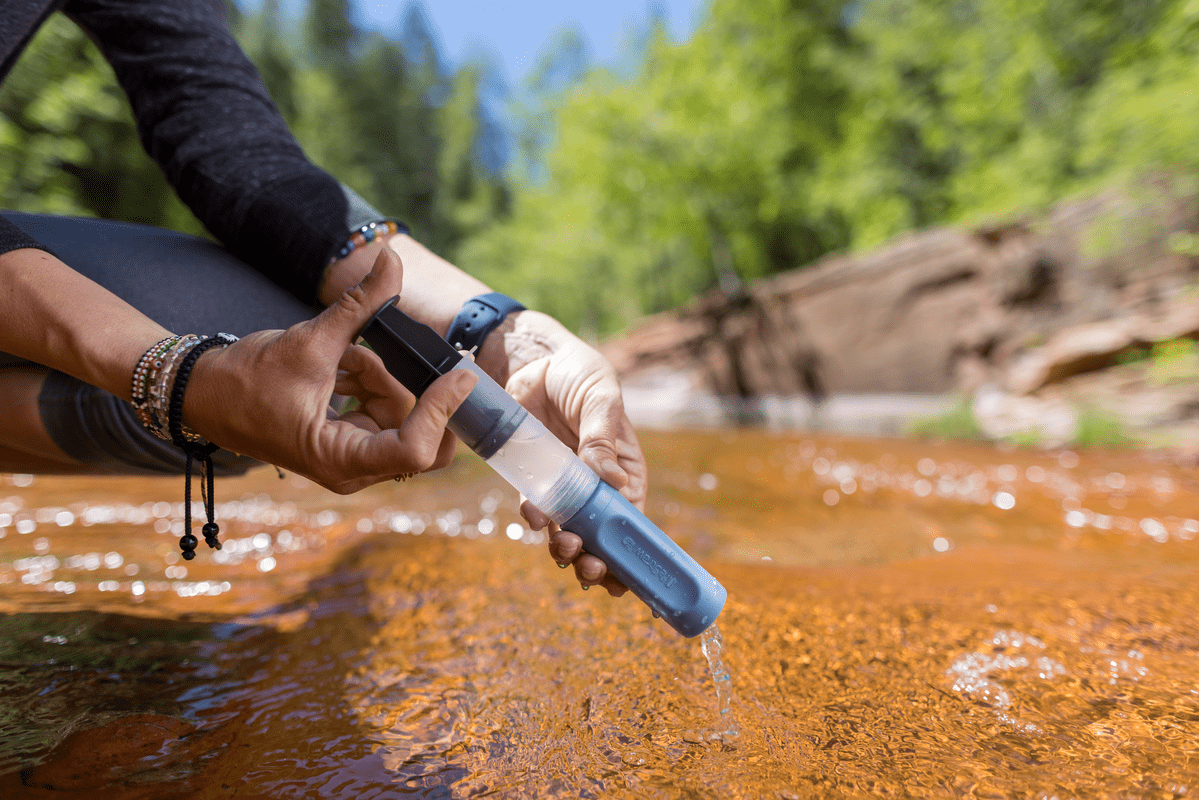 Proplachování outdoorového vodního filtru v potoce během túry