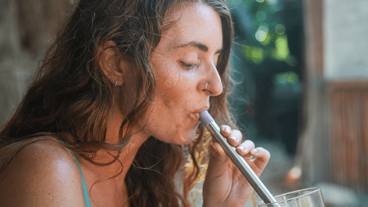 Žena pije čistou vodu z restaurace přes filtr LifeStraw Sip Apricot
