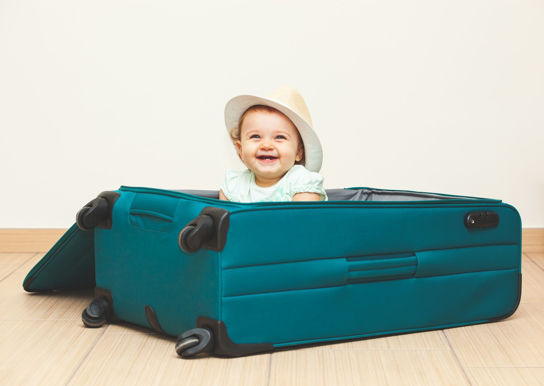 baby-girl-sitting-suitcase-floor-with-empty-background_87414-5006