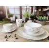 Kompletní set porcelánu Linea Botanic na stole. Miska, talíře, hrnky s lučním dekorem a žlutým lemem.