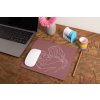 mockup of a mousepad lying on a rustic table next to a flower vase 27554