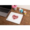 mockup of a mousepad lying on a rustic table next to a flower vase 27554