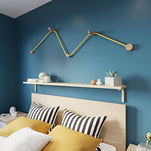 Lichterkette aus Glühbirnen im Zickzack über dem Bett an einer dunkelblauen Schlafzimmerwand