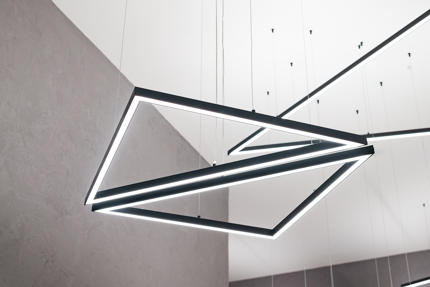 Lampy wiszące z czarnych profili LED w kształcie trapezu