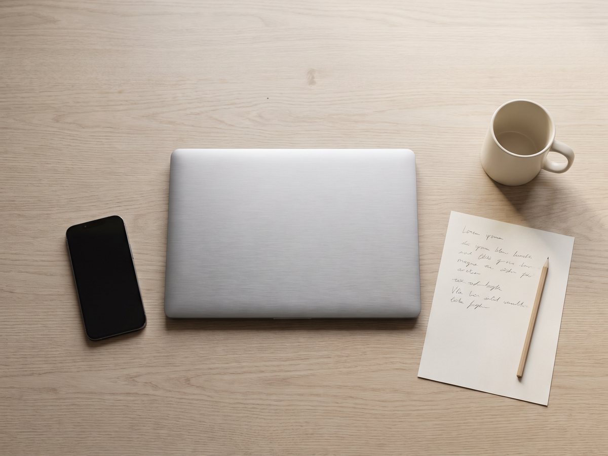 Pracovní stůl shora – zavřený notebook, odložený zhasnutý telefon a papírový seznam úkolů jako pomoc proti mozkové mlze