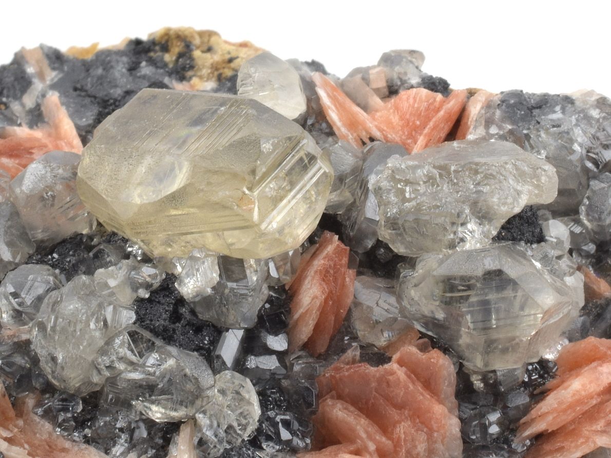 Detail velkého krystalu cerusitu s galenitem a růžovým barytem na hornině.