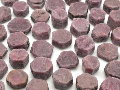 Přírodní rubínové krystaly z Tanzanie o velikosti 2–3 cm, hexagonální tvar, UV aktivní.