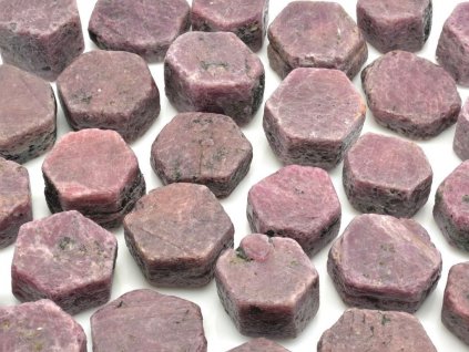 Přírodní rubíny z Tanzánie, hexagonální krystaly o velikosti 3–4 cm, UV aktivní.