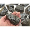 Surový hematit na dlani z Maroka o velikosti 6–9 cm a váze 200–300 g s kovovým leskem.