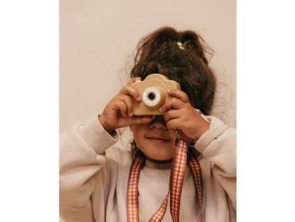 Dieťa fotografuje detským digitálnym fotoaparátom v krémovej farbe