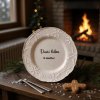 A festive winter scene A snowflake patterned white plate, emblazoned with the phrase 'Vánoční kalorie se nepočítají' (Christmas calories don't count), centered on a rustic wooden table adorned with a sprig of