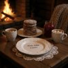 A rustic wooden table in a cozy cabin, bathed in the warm glow of a crackling fireplace A white ceramic plate with snowflake patterns rests on the table, the words Vánoční kalorie se nepočítají elegantly insc
