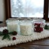 Close up lifestyle shot, a cozy scene featuring a rustic wooden table covered with a plush, snow white knitted runner, scattered with a delicate arrangement of pinecones, frosted cranberries, and sprigs of ev