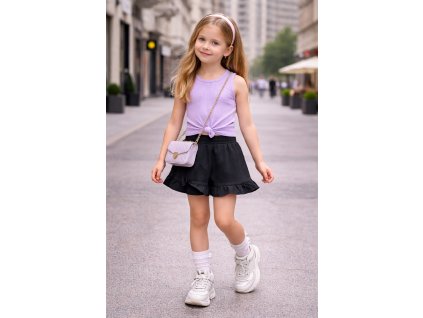 Dievča v čiernych dievčenských sukňonohaviciach s volánom a mašličkou